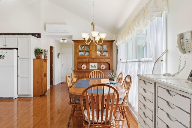 61 Pond Rd, Albion, ME 04910 - dining area with an AC wall unit, light wood finished floors, high vaulted ceiling, and an inviting chandelier