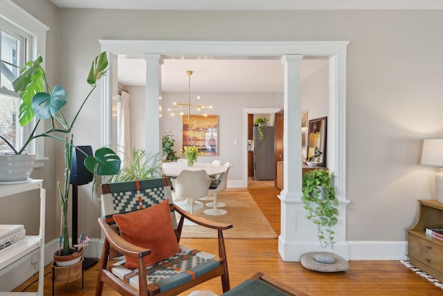 14 Codman St, Portland, ME 04103 - living area featuring decorative columns, light wood-style floors, baseboards, and a chandelier