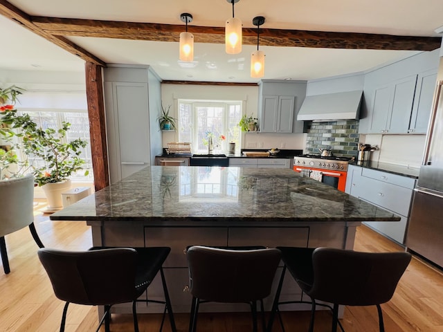 157 Ellsworth Rd, Blue Hill, ME 04614 - kitchen with premium appliances, wall chimney range hood, a kitchen breakfast bar, light wood-type flooring, and backsplash