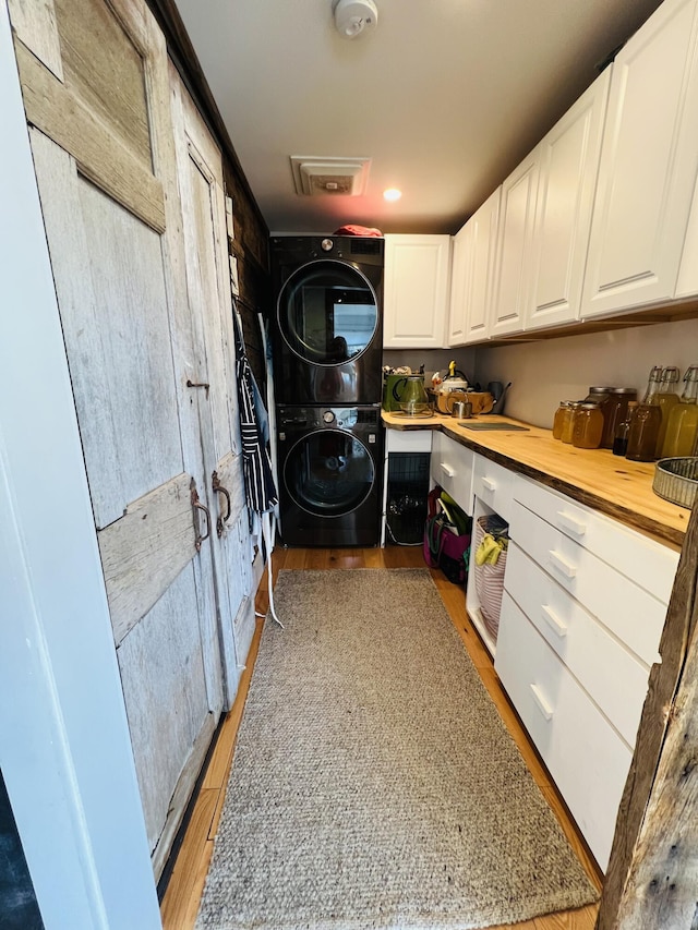 157 Ellsworth Rd, Blue Hill, ME 04614 - laundry area with stacked washer and clothes dryer, cabinet space, and light wood finished floors