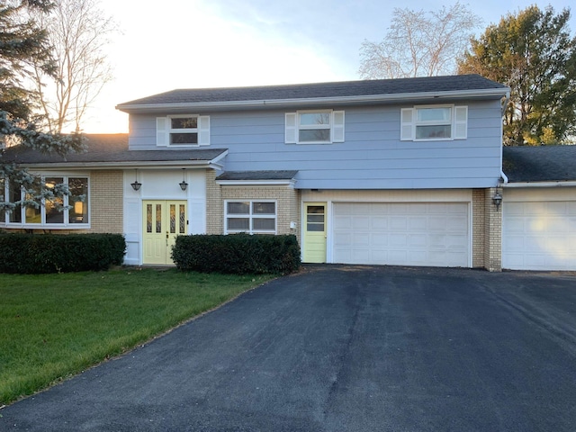 view of front of house with brick siding, asphalt driveway, a front lawn, and an attached garage