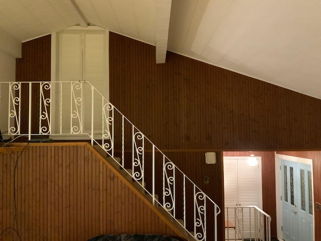 stairway featuring lofted ceiling and wood walls