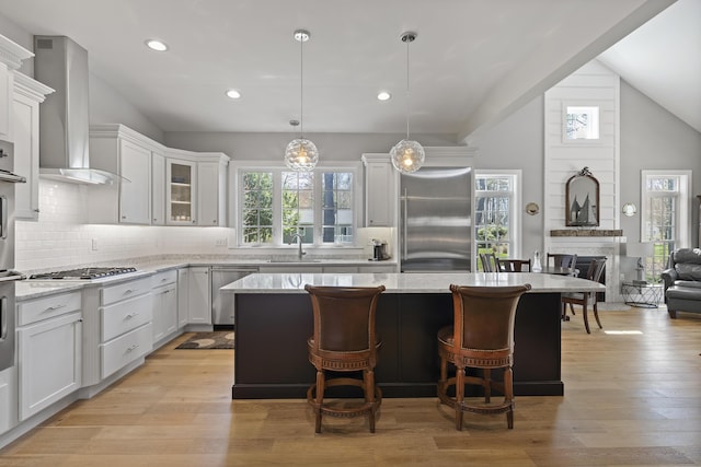 3 Flagship Cir, Kennebunk, ME 04043 - kitchen featuring appliances with stainless steel finishes, lofted ceiling, a kitchen island, wall chimney range hood, and backsplash