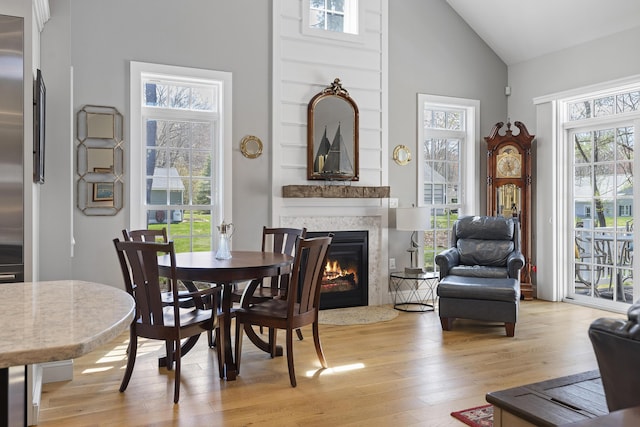 3 Flagship Cir, Kennebunk, ME 04043 - dining room featuring high vaulted ceiling, light wood-type flooring, a fireplace with flush hearth, and healthy amount of natural light