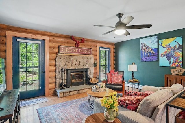 370 Point Rd, Belgrade, ME 04917 - living area featuring rustic walls, wood finished floors, a fireplace, a baseboard heating unit, and a ceiling fan