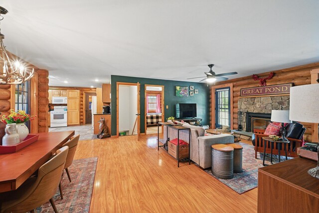 370 Point Rd, Belgrade, ME 04917 - living area with a stone fireplace, log walls, light wood finished floors, and ceiling fan with notable chandelier