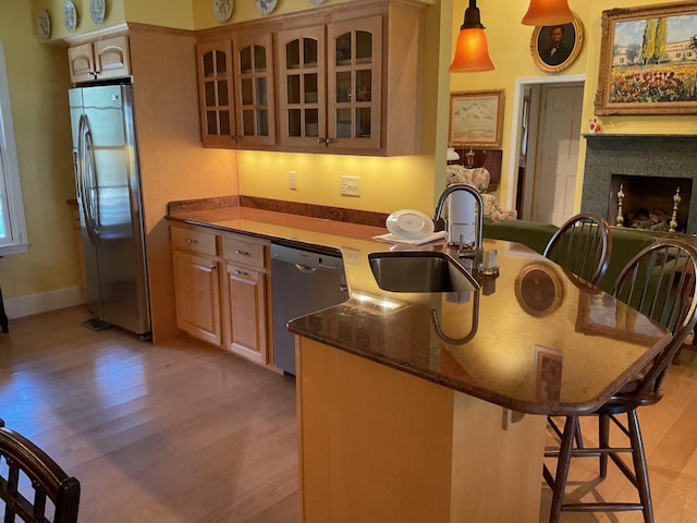 kitchen with a sink, a kitchen breakfast bar, stainless steel appliances, and light wood finished floors