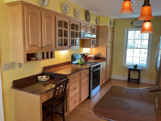 kitchen featuring pendant lighting, glass insert cabinets, black range with gas stovetop, under cabinet range hood, and light wood-style flooring