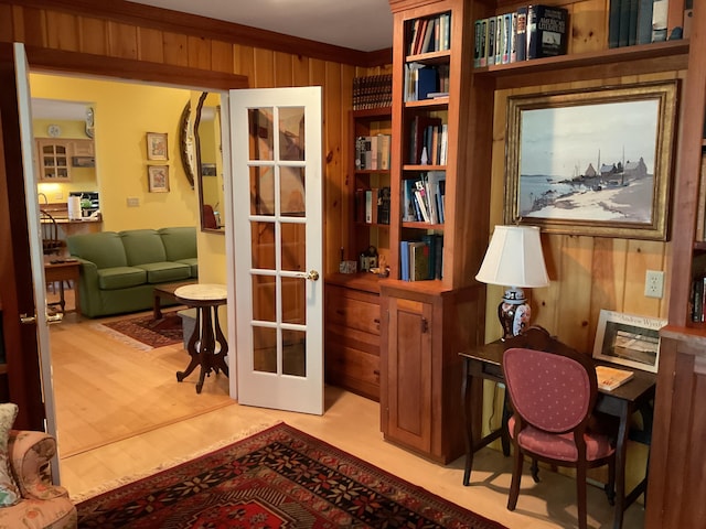 home office featuring light wood-style floors, french doors, and wood walls