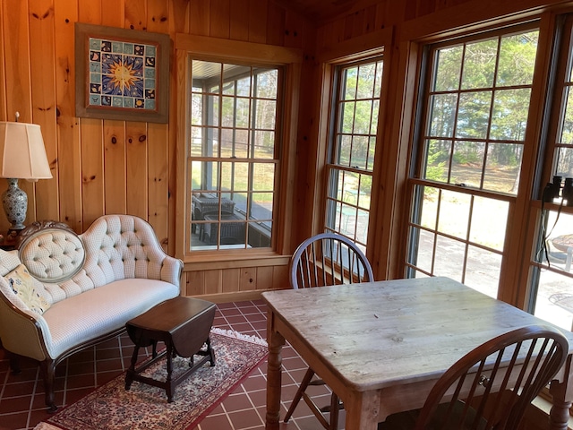 dining room with wooden walls and dark tile patterned floors