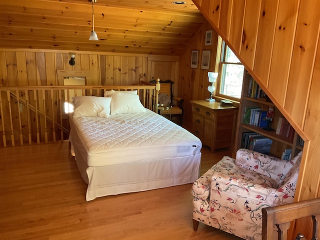 bedroom featuring wood walls, vaulted ceiling, wooden ceiling, and wood finished floors