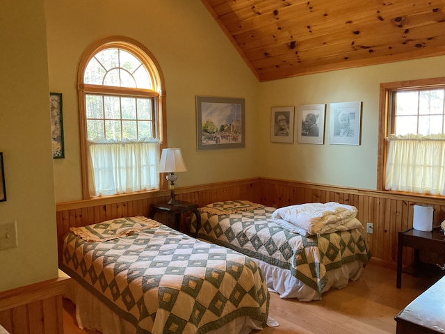 bedroom featuring wood finished floors, a wainscoted wall, multiple windows, and wooden ceiling
