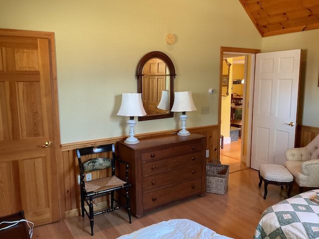 bedroom featuring vaulted ceiling, wainscoting, wood walls, wood finished floors, and wooden ceiling