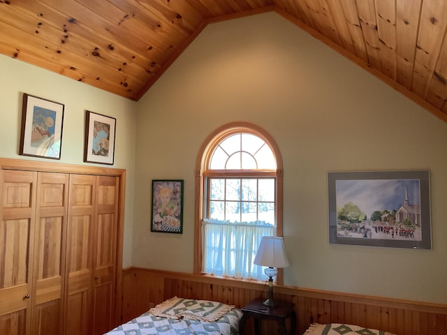 bedroom featuring a wainscoted wall, wooden walls, vaulted ceiling, and wooden ceiling