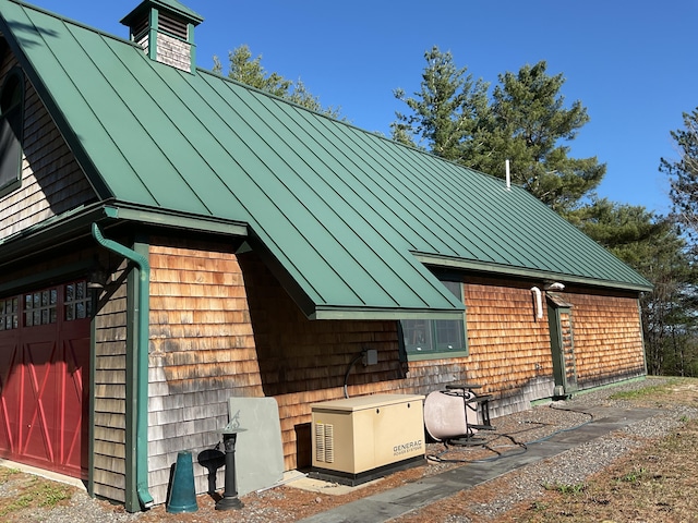 rear view of house featuring a standing seam roof, metal roof, and a garage