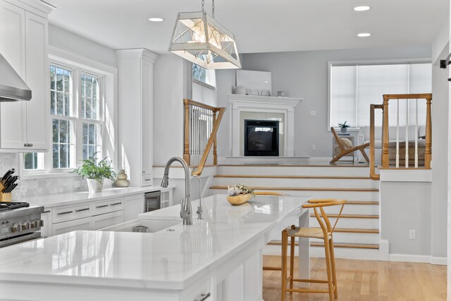 36 Fort Hill Ave, York, ME 03909 - kitchen featuring white cabinets, an island with sink, a sink, and light wood-style floors
