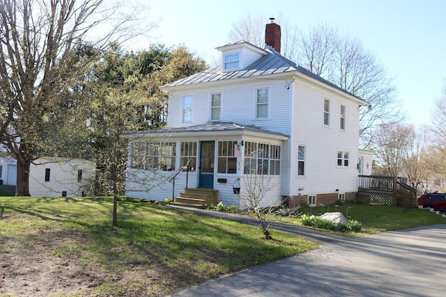 american foursquare style home featuring a standing seam roof, metal roof, a sunroom, and a front lawn