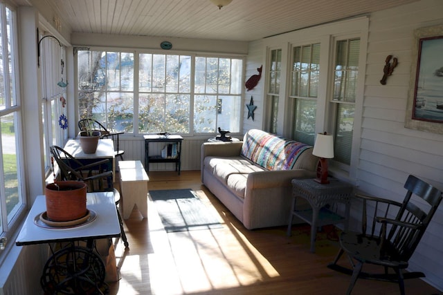 sunroom featuring wood walls, wood finished floors, and a wealth of natural light