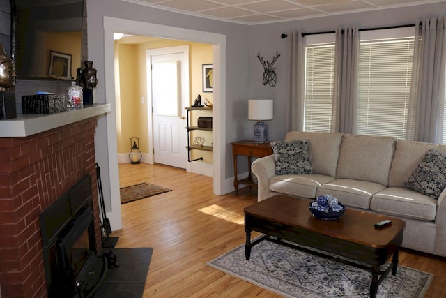 living area featuring light wood-type flooring, baseboards, a wealth of natural light, and a fireplace