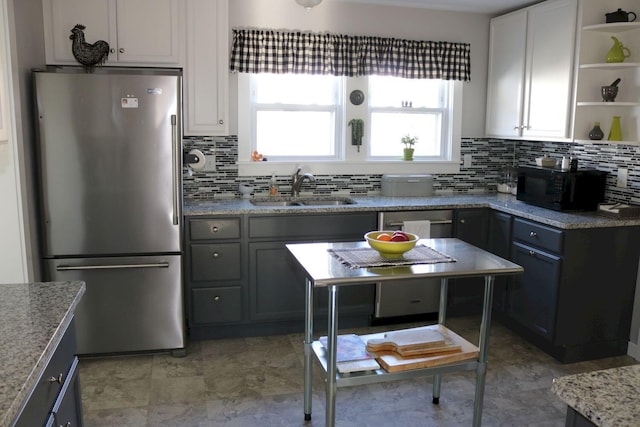 kitchen featuring freestanding refrigerator, open shelves, decorative backsplash, black microwave, and a sink