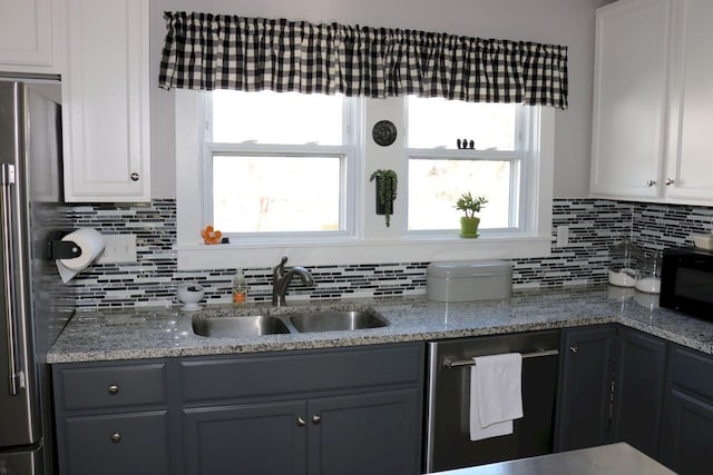kitchen with a sink, decorative backsplash, light stone countertops, and stainless steel appliances
