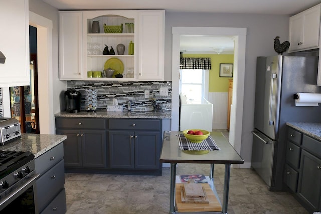 kitchen with light stone counters, appliances with stainless steel finishes, white cabinets, and washer / clothes dryer