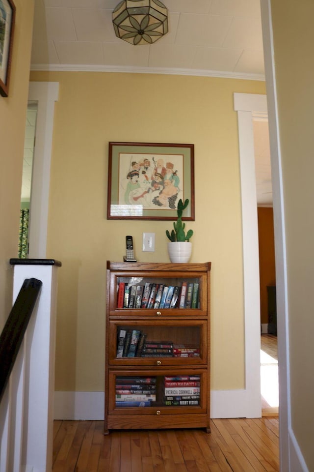 hall featuring baseboards, ornamental molding, and wood-type flooring