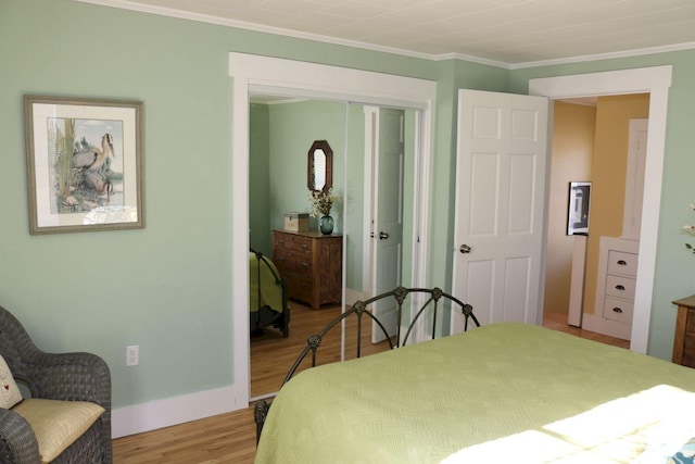 bedroom with crown molding, baseboards, a closet, and wood finished floors