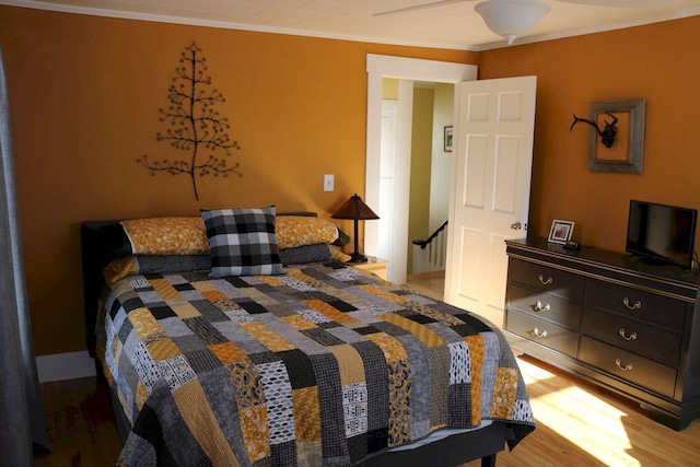 bedroom featuring ornamental molding and wood finished floors