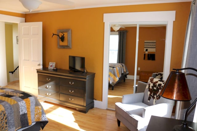 bedroom with light wood-style floors, baseboards, and crown molding