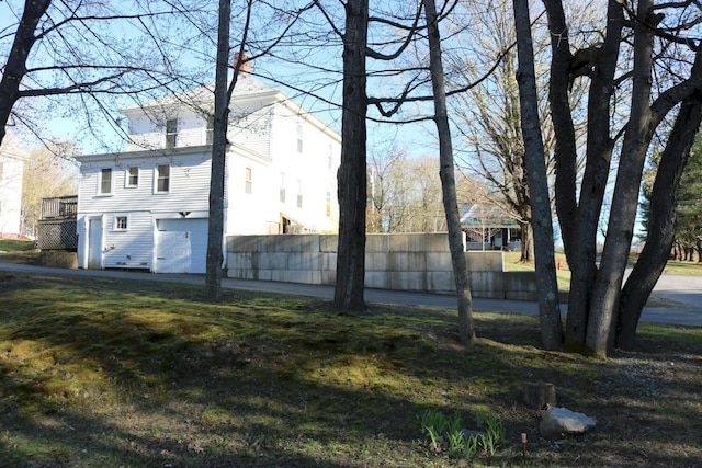 view of side of home with fence, an attached garage, and a chimney