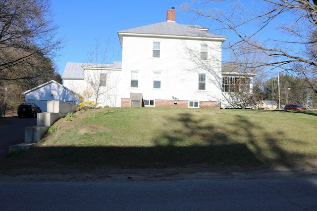 back of house featuring an outdoor structure, a yard, and a chimney