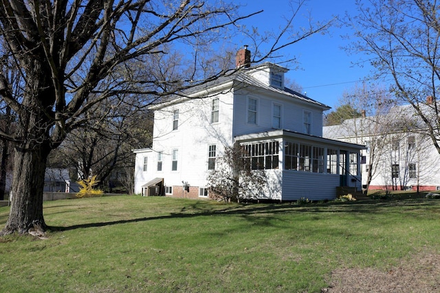 back of house featuring a yard, a chimney, and a sunroom
