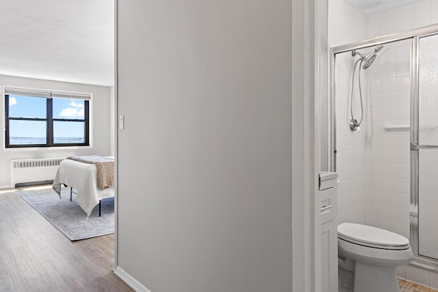 45 Eastern Promenade Unit 1E, Portland, ME 04101 - bathroom with a stall shower, wood finished floors, toilet, radiator heating unit, and ensuite bathroom