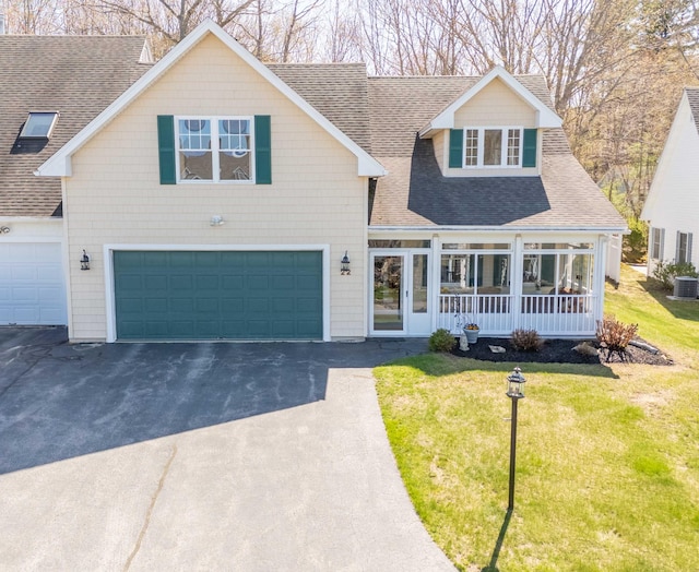 view of front of property featuring an attached garage, a front yard, a shingled roof, and driveway