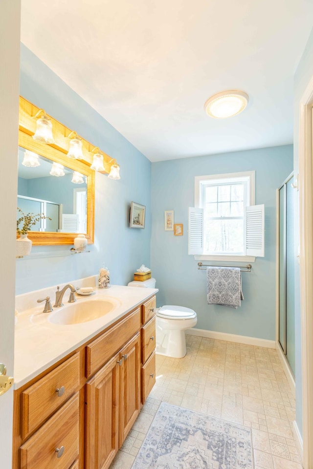 full bathroom featuring a stall shower, vanity, toilet, and baseboards