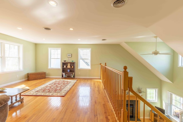 sitting room with baseboards, light wood finished floors, an upstairs landing, and visible vents