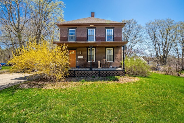 view of front of home with a porch, a chimney, and a front yard