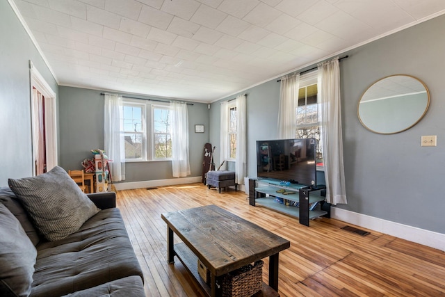living area featuring crown molding, a healthy amount of sunlight, hardwood / wood-style floors, and visible vents