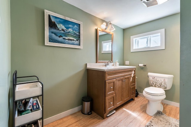 half bath with vanity, baseboards, toilet, and wood finished floors