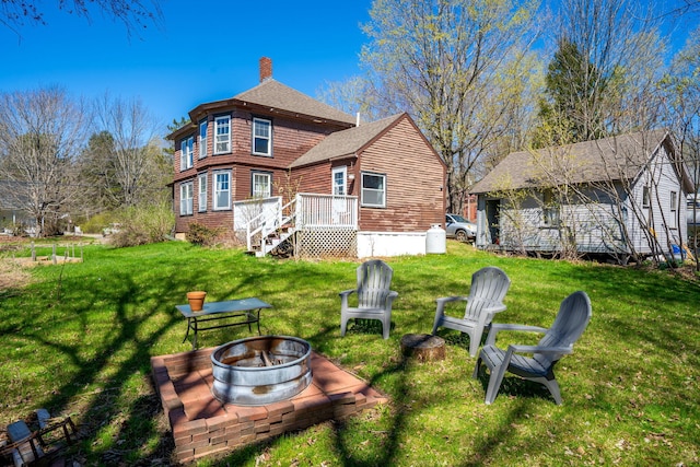 rear view of house featuring a lawn, an outdoor fire pit, roof with shingles, and a chimney