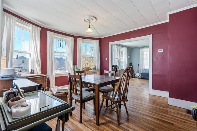 dining room featuring baseboards, ornamental molding, and hardwood / wood-style floors