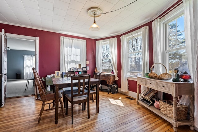 dining space with crown molding, baseboards, and hardwood / wood-style floors