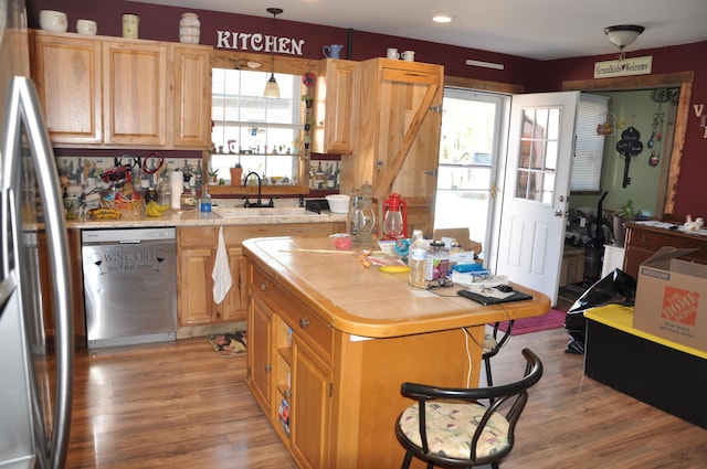kitchen featuring a sink, stainless steel appliances, tile countertops, and a wealth of natural light