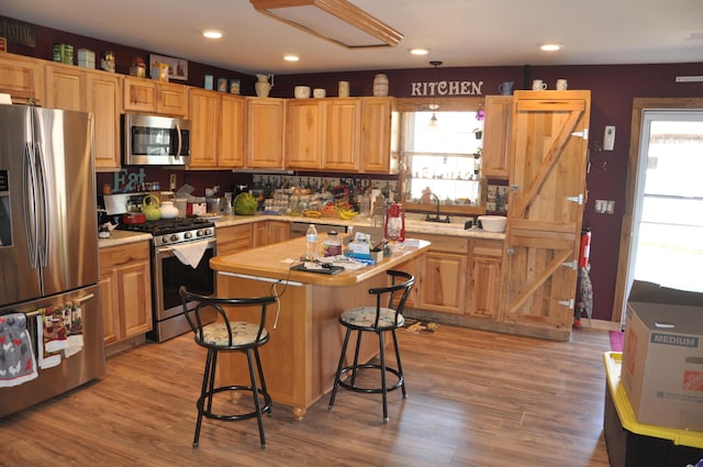 kitchen with a healthy amount of sunlight, appliances with stainless steel finishes, a kitchen island, and light countertops