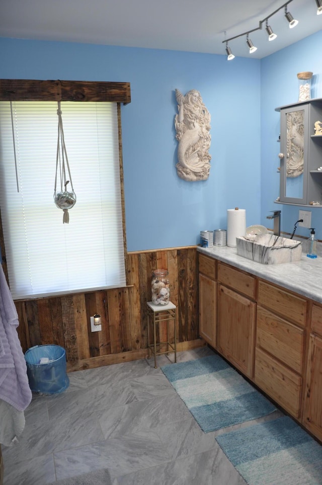 bathroom featuring a wainscoted wall, vanity, and wood walls