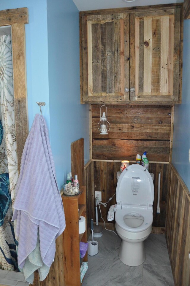 bathroom featuring wooden walls and toilet