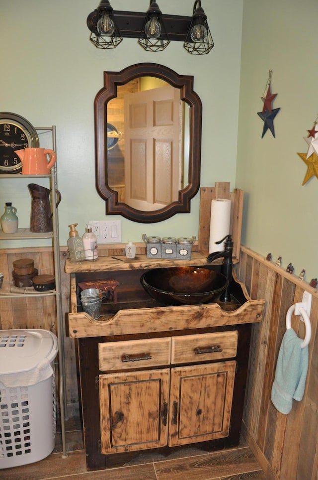 bathroom with a wainscoted wall, wood walls, wood finished floors, and vanity