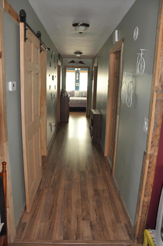 hall featuring dark wood-type flooring and a barn door