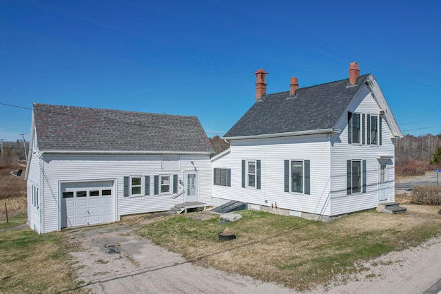1357 Indian River Rd, Addison, ME 04606 - back of property featuring a chimney, roof with shingles, a garage, asphalt driveway, and a lawn